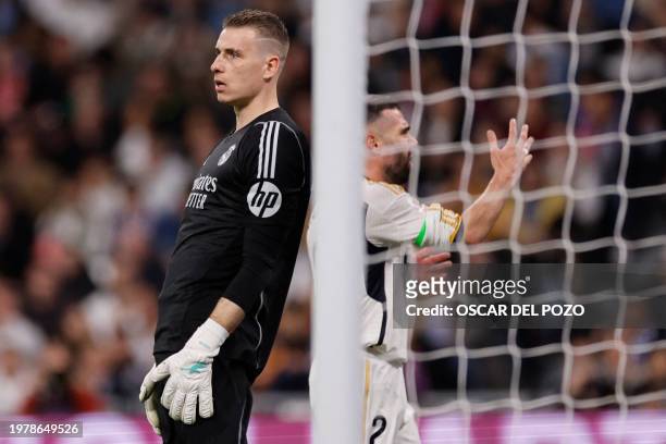 Real Madrid's Ukrainian goalkeeper Andriy Lunin and Real Madrid's Spanish defender Dani Carvajal react to the equalizing goal scored by Atletico...