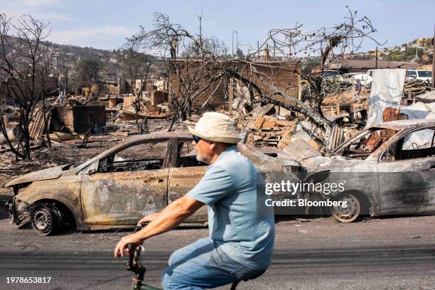 Resident rides a bicycle past destroyed homes and burned vehicles following wildfires in Vina del Mar, Valparaiso region, Chile, on Sunday, Feb. 4,...