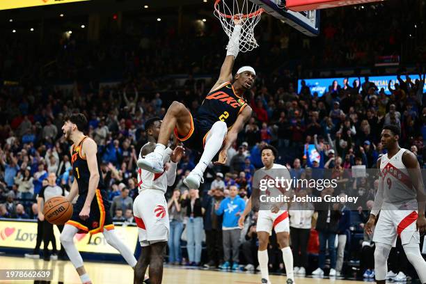 Shai Gilgeous-Alexander of the Oklahoma City Thunder hangs from the rim after a dunk in the second overtime against the Toronto Raptors at Paycom...