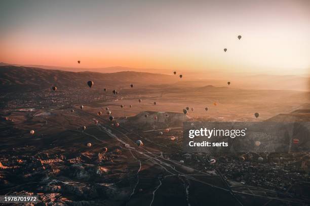 hot air balloons flying over rock formations at sunrise in cappadocia, goreme, turkey - rock hoodoo stockfoto's en -beelden