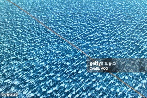Aerial view of flock of sheep crossing an ice lake to an island in the middle of the lake for enough grass in winter on February 1, 2024 in Lhoka,...