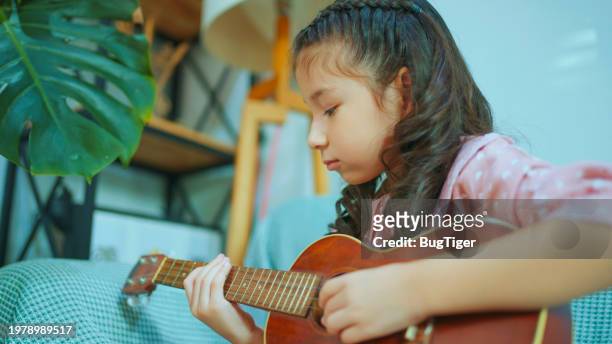 kleines chinesisches mädchen singt und spielt ukulele. - tiny mexican girl stock-fotos und bilder