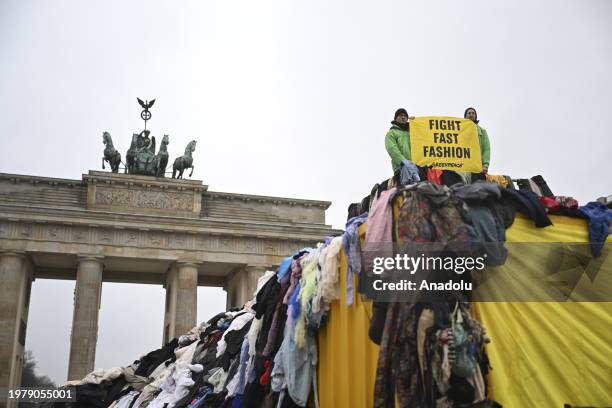 An activist holds a placard on top of the textile waste as a group of environmental activists of Greenpeace, an independent global campaigning...