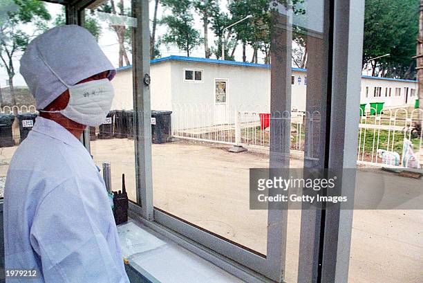 Health worker wearing a surgical mask watches the access to the restricted section of the newly built 1000 bed SARS hospital in Xiaotangshan hospital...