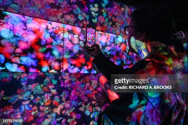 Visitor takes a photo at an exhibition during a media tour of the new location for the digital art of Japanese collective "teamLab" at the recently...