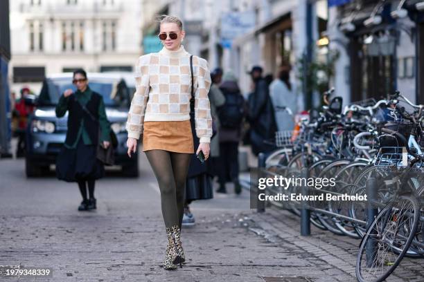 Guest wears sunglasses, a white and beige checkered / checked pattern printed turtleneck ribbed wool pullover with shoulder pads, a beige / brown...