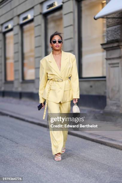 Ellie Delphine wears sunglasses , a pastel pale yellow oversized blazer jacket , a belt, flared pants , outside Mark Kenly Domino Tan, during the...