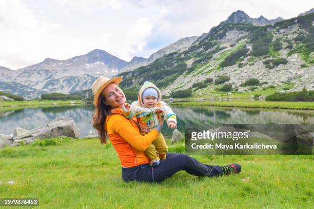 mother with baby boy by a mountain lake enjoying beautiful sunny day - bansko stock pictures, royalty-free photos & images