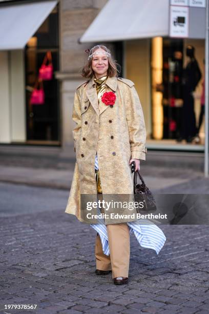 Guest wears a veil over the head, a golden shiny gathered mini dress, a blue and white bi color oversized shirt over the waist, a trench coat, beige...