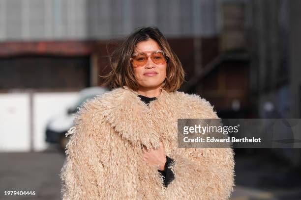Guest wears brown transparent sunglasses, a beige pastel pale brown fluffy oversized faux fur coat, outside Gestuz, during the Copenhagen Fashion...