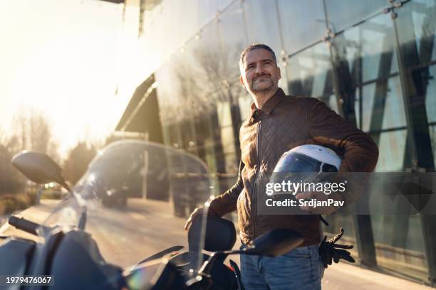 mid-adult caucasian man, near his motorcycle at the city - crash helmet stock pictures, royalty-free photos & images