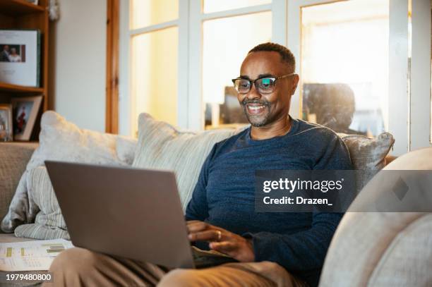 mature black man working on laptop at home - ethnicity stock pictures, royalty-free photos & images
