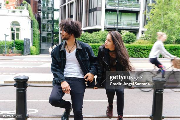 relaxed couple on city street railing - denim coat stock pictures, royalty-free photos & images