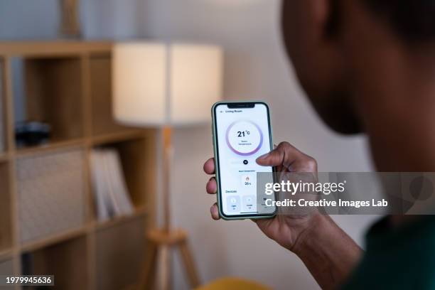 man controlling home temperature remotely - adjustable monitor stock pictures, royalty-free photos & images