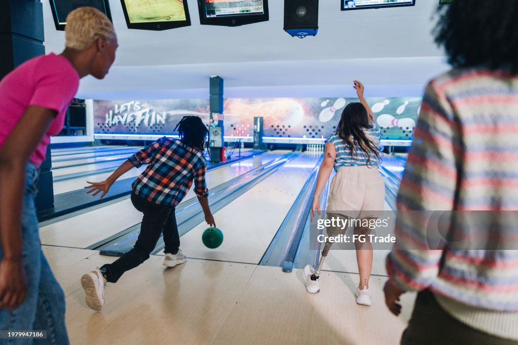 Friends throwing a bowling ball at a bowling club - including a person with a prosthesis leg