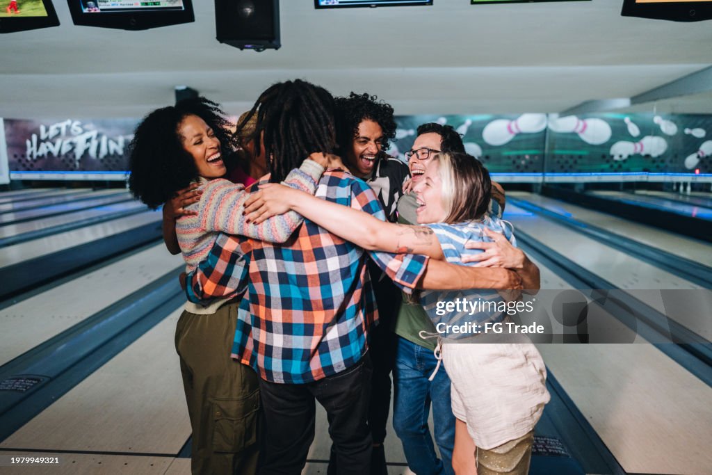 Amigos abrazándose y celebrando en un club de bolos