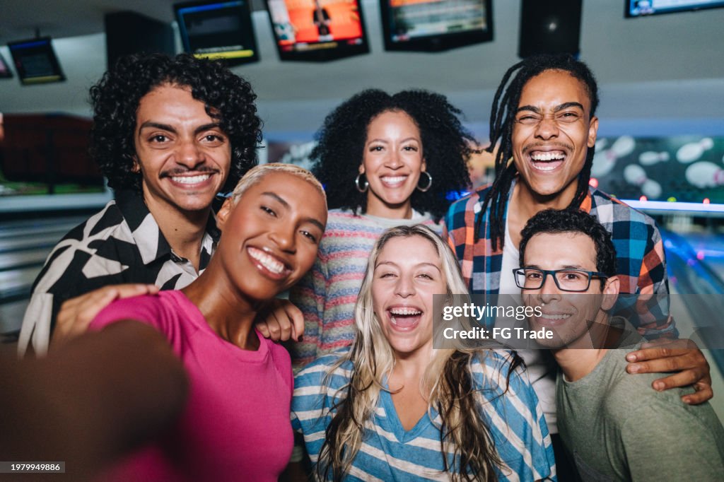Amigos tirando selfies em um clube de boliche