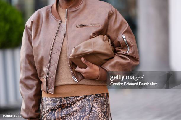 Loicka Grace wears a brown leather bomber jacket, a midi snake pattern printed leather skirt , a brown leather pouch bag, outside Mark Kenly Domino...