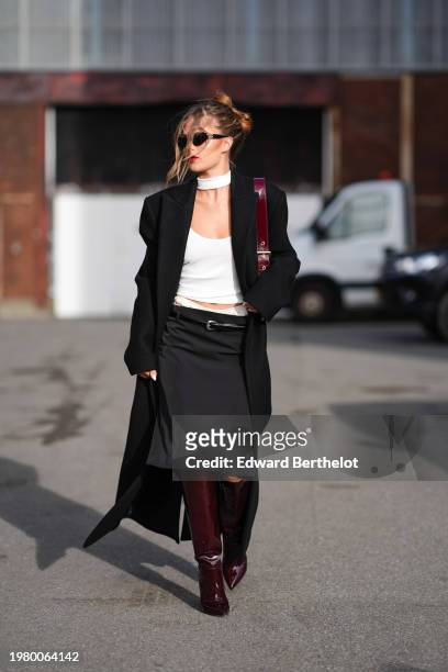 Guest wears sunglasses , red lipstick , make-up, a choker, a low-neck white t-shirt, a black long coat, thin leather belt, a satin midi skirt ,...