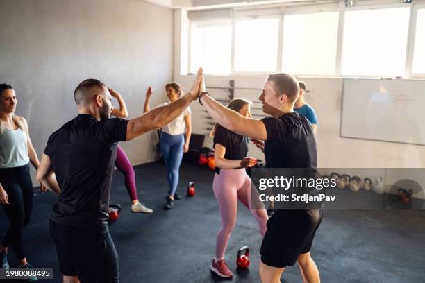 group of people interchange high-five with an cross trainer after an exercise - high five interchange stock pictures, royalty-free photos & images