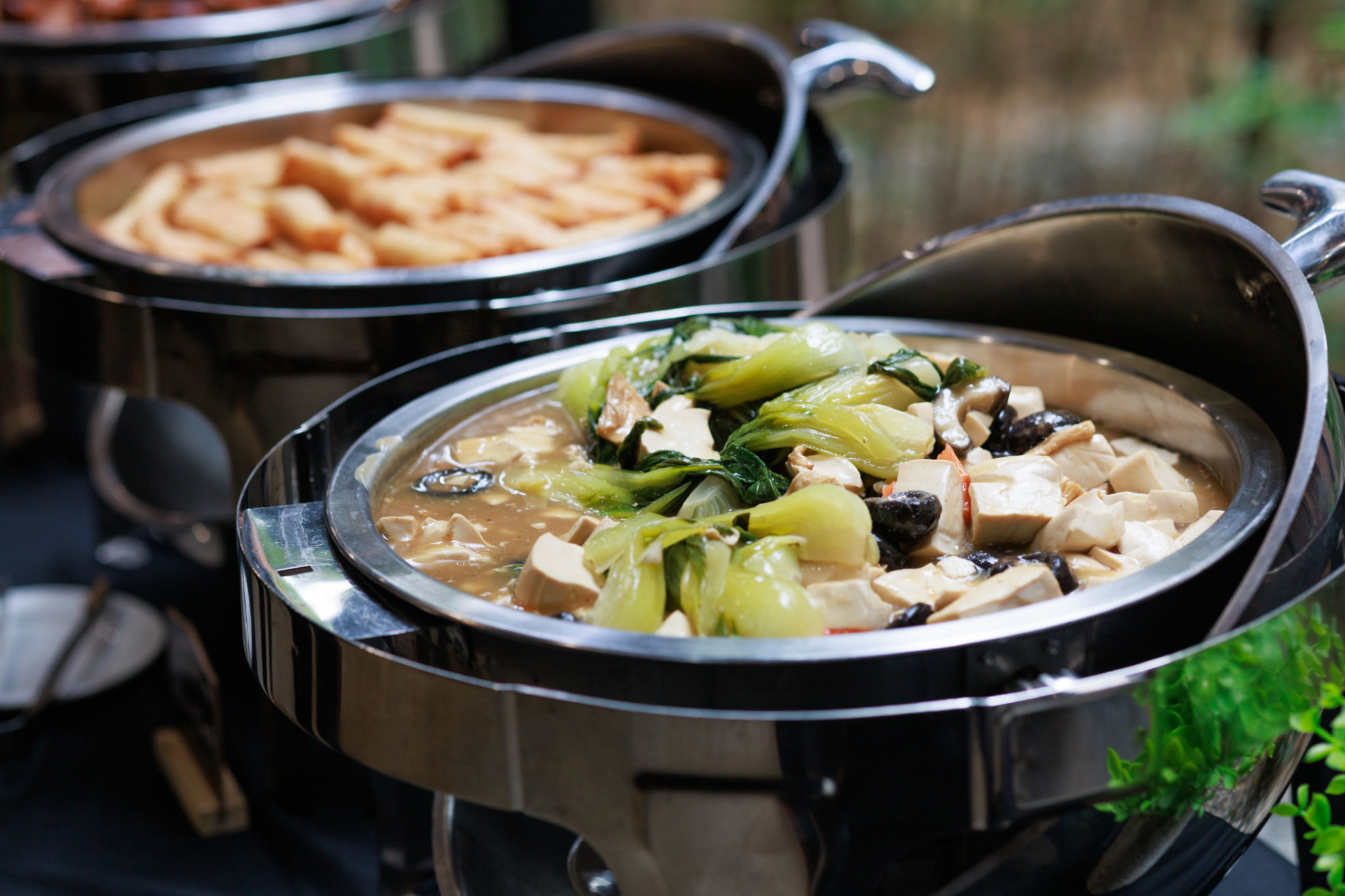 A variety of Asian food is displayed in chafing dishes on a buffet table, offering a diverse and tempting selection for diners. A variety of Asian food is displayed in chafing dishes on a buffet table, offering a diverse and tempting selection for diners.