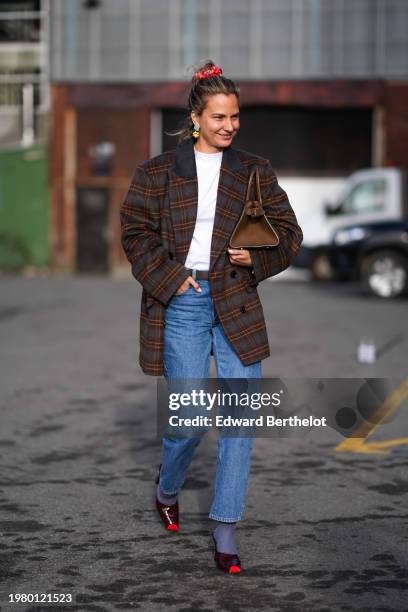 Guest wears a red hair scrunchie, earrings, a white t-shirt, a brown checkered / checked pattern printed oversized blazer jacket, a brown leather...