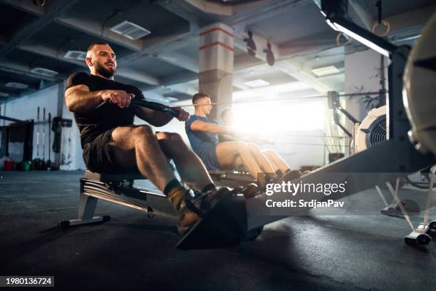 male athletes exercise on a rowing machine at the gym - exercise machine stock pictures, royalty-free photos & images