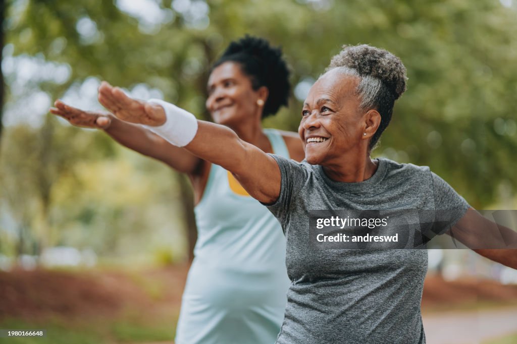 Two women friends doing exercises together senior and mature