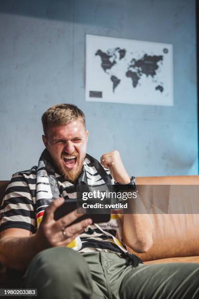 young man watching soccer game at home - sports betting stock pictures, royalty-free photos & images