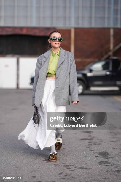 Guest wears green sunglasses from Loewe, a green shirt, a gray oversized blazer jacket , a white gathered midi dress, brown leopard print pattern...