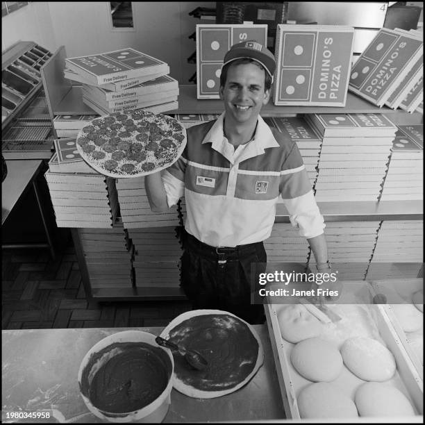 Portrait of American businessman and Domino's Pizza franchise owner Frank Meeks as he holds a pepperoni pizza in his Duke Street storefront,...