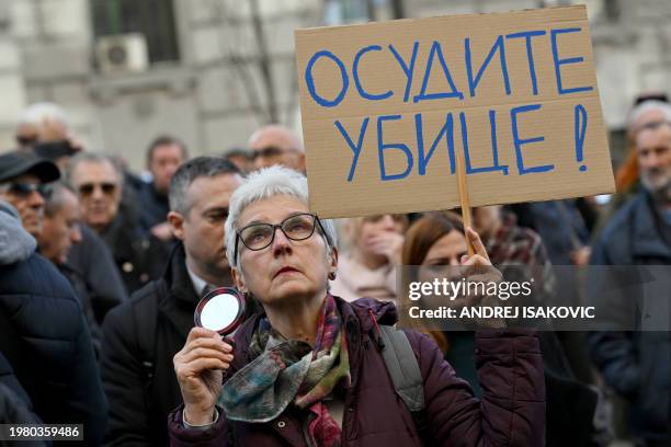 Woman holds a placard reading "Condemn the murderers!", as protesters gather in Belgrade on February 5 to protest against last week's ruling by an...