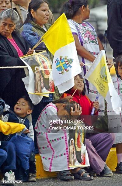 Believers await 01 August 2002 the passage of Pope John Paul II along the Paseo de la Reforma, in Mexico City, in his way to the Basilica of...