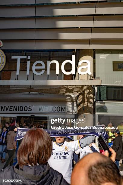 real madrid fan taking a photo with the real madrid scarf against the club's official store at the santiago bernabeu stadium. - real madrid fans stock pictures, royalty-free photos & images