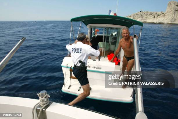 Un membre de la police maritime monte à bord du bateau d'un plaisancier pour contrôler son permis bateau et son équipement de sécurité, le 02 août...
