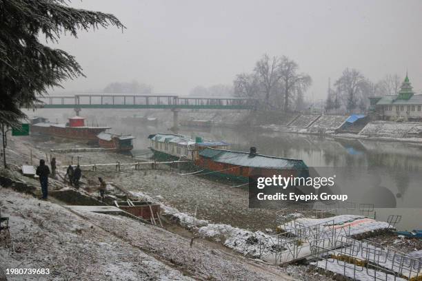 February 03 Srinagar, India : Houseboats are seen on the snowy banks of River Jhelum in Srinagar.