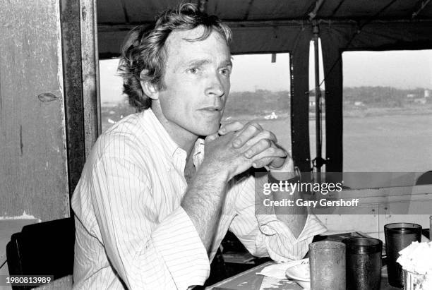 View of American television host Dick Cavett seated at a table during an interview at the Dock Restaurant, Montauk Point, Long Island, New York,...