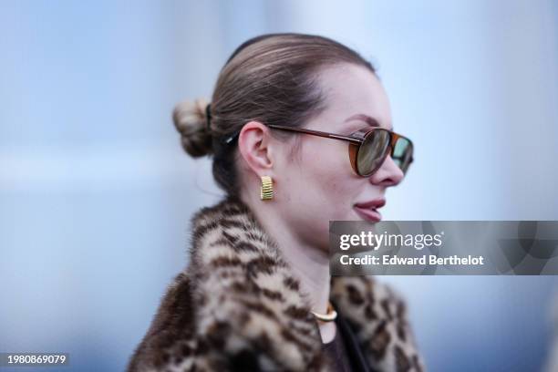 Guest wears sunglasses, golden earrings, lipstick ; hair bun, leopard print pattern fluffy coat , outside Munthe, during the Copenhagen Fashion Week...