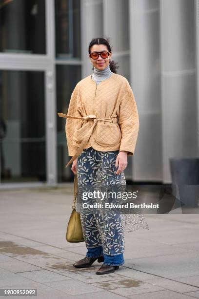 Guest wears orange sunglasses, a gray turtleneck , a beige padded jacket , a mesh floral print skirt, a yellow bag, blue denim jeans pants , pointed...