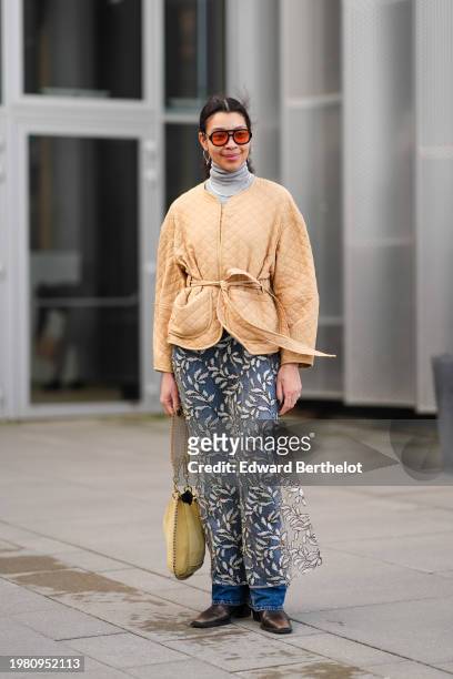 Guest wears orange sunglasses, a gray turtleneck , a beige padded jacket , a mesh floral print skirt, a yellow bag, blue denim jeans pants , pointed...