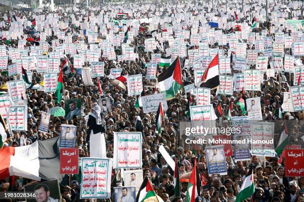 Houthi followers lift rifles, anti-U.S. And Israel emblems, placards depicting Houthi leader Abdul Malek Bard Alden Al-Houthi, and flags of Yemen and...