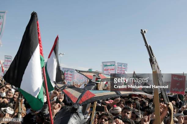 Houthi followers lift rifles, anti-U.S. And Israel emblems, placards depicting Houthi leader Abdul Malek Bard Alden Al-Houthi, and flags of Yemen and...