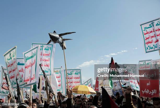 Houthi followers lift rifles, anti-U.S. And Israel emblems, placards depicting Houthi leader Abdul Malek Bard Alden Al-Houthi, and flags of Yemen and...