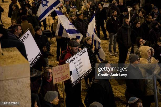 Protesters hold signs and flags in front of the UNRWA office in Jerusalem during a demonstration calling for the expulsion of the UNRWA office from...