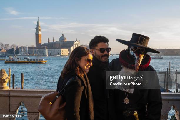 People taking a photo with a man wearing typical Venice Carnival costumes and masks are seen Venice, Italy, on February 2nd, 2024. San Giorgio...