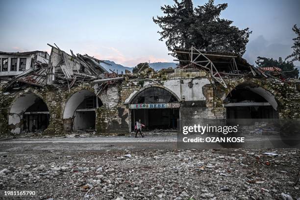 Woman walks next to a damaged building in Antakya, Hatay province, on February 5 after one year the February 2023 earthquake. The disaster, which...