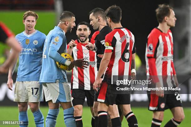 Kyle Walker of Manchester City speaks to Referee Jarred Gillett as Neal Maupay of Brentford gestures during the Premier League match between...