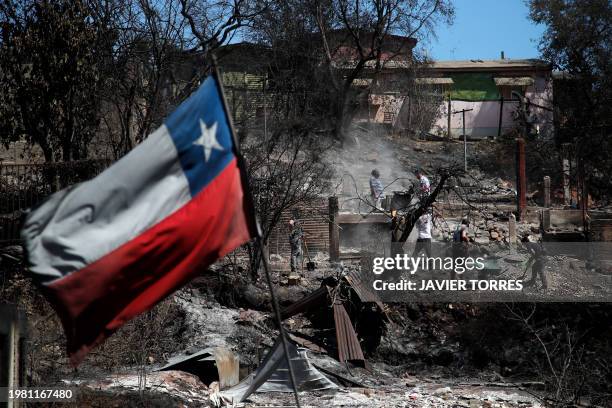 Chilean flag waves as neighbours clean their lands and burnt homes in Villa Independencia, Valparaiso region, Chile on February 5, 2024. The death...