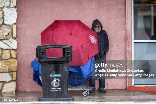 Los Angeles, CA A man with his belongings stands under a building awning to keep out of the heavy rain on Van Nuys Blvd. In Pacoima on Monday,...