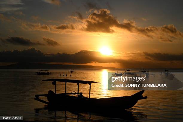 People watch sunrise at Sanur beach on the Indonesian resort island of Bali on February 6, 2024.